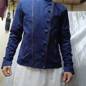 May include: A navy blue jacket with a high collar, asymmetrical zipper, and button closure. The jacket has a suede-like texture and features two front pockets and a zipper on the sleeve. The jacket is a stylish outerwear option.