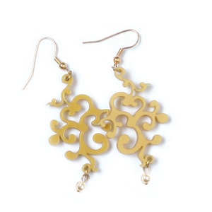 May include: A pair of gold filigree earrings with a dangling pearl accent. The earrings are made of a delicate, intricate design.