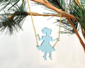 Op de afbeelding: Een lichtblauwe glazen ketting met een hanger met het silhouet van een meisje op een schommel. De ketting is van goud.