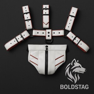 May include: A white leather harness and brief set with red accents and black hardware. The set includes a harness with multiple straps and a brief with a zipper. The Boldstag logo is visible in the bottom right corner.
