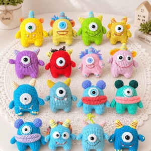 May include: A collection of sixteen small, colorful crocheted monster dolls arranged in four rows. Each creature features a unique combination of bright yarn colors, single or multiple eyes, small horns, and stitched mouths, all crafted in amigurumi style.
