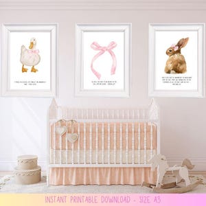 May include: Three framed watercolor prints with a nursery theme. The prints feature a white duck with a pink bow, a pink bow, and a brown bunny with a pink flower. Each print has a quote in black text. A crib and toy horse are in the foreground.