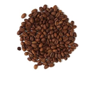 Puede incluir: Un montón de granos de café tostados, de color marrón medio, sobre un fondo blanco. Los granos, de forma ovalada, parecen recién tostados y ligeramente brillantes. Vista superior.
