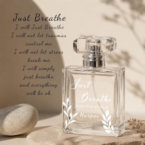 Peut inclure: Un flacon de parfum en verre transparent avec un bouchon à facettes style cristal. L'avant du flacon présente un texte imprimé blanc indiquant Just Breathe, Every thing will be ok, et le nom Harper, encadré par deux illustrations de feuilles.