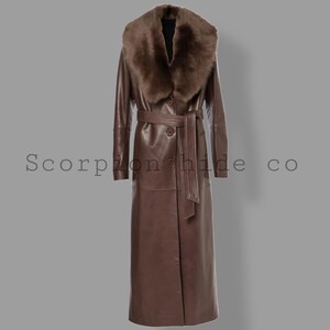 May include: A long, brown leather coat with a fur collar and a matching belt. The coat has a button closure and is floor-length. The text "Scorpion hide co" is printed on the coat.