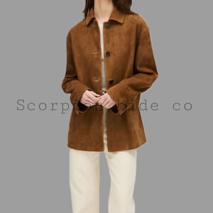 Puede incluir: Chaqueta de ante marrón con cierre de botones y cuello. La chaqueta es de longitud media y tiene mangas largas. El texto "Scorpion hide co" es visible en la imagen.