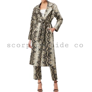 May include: A snakeskin-patterned coat and matching pants set. The coat features a belted waist, long sleeves, and pockets. The pants are cropped. The outfit is in shades of brown, beige, and black. The text "scorpion hide co" is visible.