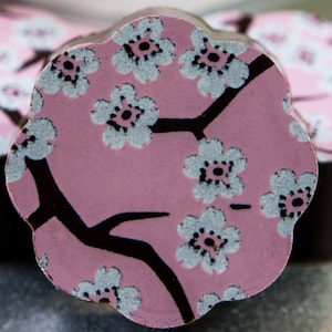 May include: A pink chocolate with a black and white cherry blossom design.