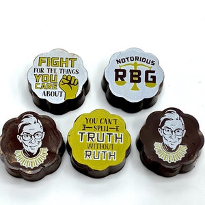May include: Five chocolate candies with different designs featuring Ruth Bader Ginsburg. One candy has a portrait of Ginsburg, another has a scale of justice and the text "Notorious RBG", another has the text "You can't I-SPELL-I TRUTH without RUTH", and two have portraits of Ginsburg.