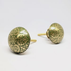 May include: Two decorative cabinet knobs with a floral design. The knobs are round with a green and gold colour scheme. The floral pattern is embossed on the surface, and the stems are gold.