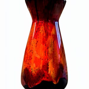 May include: A ceramic vase with a flared top and a rounded base. The vase has a glossy finish with a blend of colours, including deep red, orange, and black. The design has a dripped effect, creating a unique, artistic look.