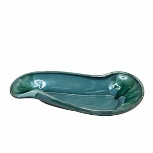 May include: An elongated, asymmetrical ceramic dish with a glossy finish in shades of deep teal and forest green. The bowl features a smooth, curved rim and a concave center, showcasing a variegated glaze pattern that transitions between dark and light tones.
