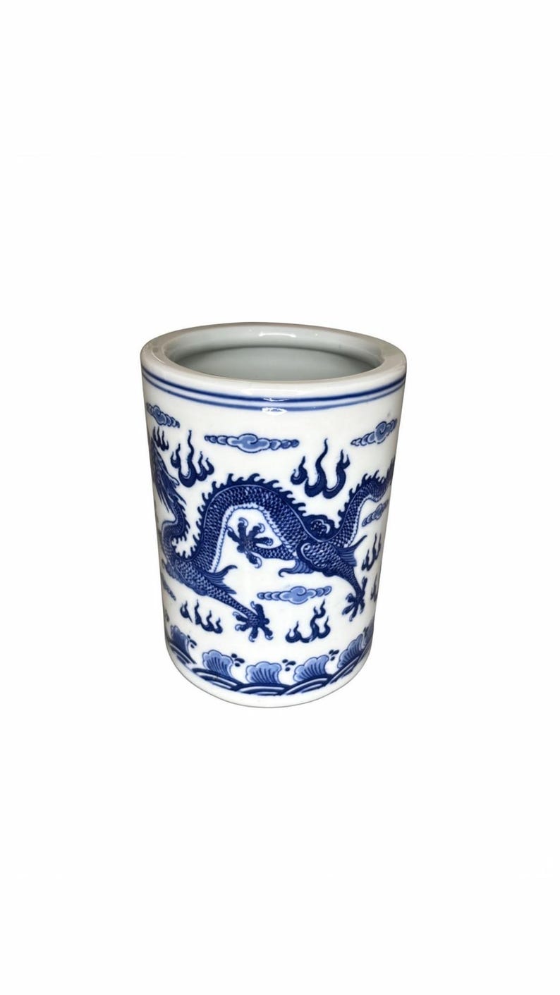 May include: A cylindrical ceramic container with a blue and white dragon design. The container features a detailed illustration of a dragon amidst clouds and flames. The top and bottom edges are accented with blue bands, creating a classic aesthetic.
