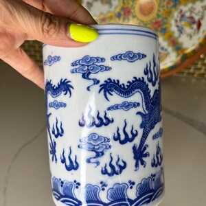 May include: White ceramic mug with a blue dragon and cloud design. The mug features a cylindrical shape and is decorated with a traditional Asian-inspired pattern. The blue and white color scheme gives it a classic and elegant look.