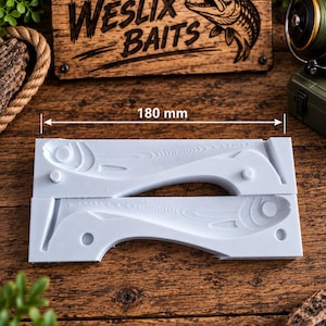Könnte beinhalten: Eine weiße, zweiteilige Silikonform zum Gießen von Angelködern mit einer fischförmigen Vertiefung und detaillierten Schuppenstrukturen. Die Form ist 180 mm lang. Ein Holzschild darüber zeigt den Text WESLIX BAITS mit einer Fischgrafik.