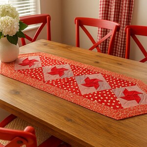 Peut inclure: Chemin de table rouge et blanc à motifs de pinwheel. Le chemin de table est posé sur une table en bois, avec des chaises rouges en arrière-plan. Le chemin de table présente un motif à pois rouges et blancs avec des carrés de pinwheel.