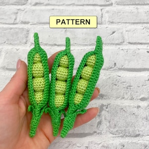 Puede incluir: Tres vainas de guisantes de ganchillo hechas a mano, cada una llena de guisantes verde claro. Las vainas son de color verde vibrante, y la palabra "PATTERN" se muestra en un rectángulo amarillo.