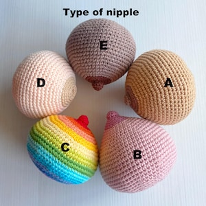 Könnte beinhalten: Fünf gehäkelte Brustmodelle in verschiedenen Farben und Designs, beschriftet mit A bis E. Eines ist regenbogenfarben, die anderen sind in verschiedenen Rosa-, Beige- und Brauntönen gehalten. Der Text "Type of nipple" befindet sich oben.