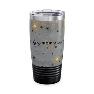 May include: A stainless steel travel tumbler with a gray background and a black and gold dragon design. The tumbler features a black base and a silver lid. The design includes gold stars and black spider-like shapes.