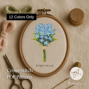 May include: A cross-stitch PDF pattern featuring a bouquet of blue forget-me-nots in a wooden embroidery hoop. The text "forget me not" is below the flowers. The image also includes scissors, thread, and a thimble. The text "12 Colors Only" is in a black box.