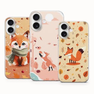 May include: Three phone cases with autumn-themed designs. One case features a cute fox wearing a scarf, another shows a fox reaching for a bird, and the third has a fox with fall leaves. The cases have a clear border.
