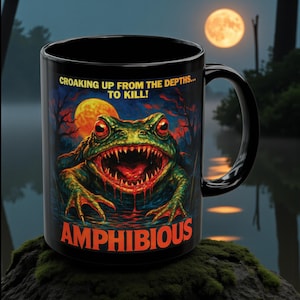 May include: Black ceramic mug featuring a menacing green frog with red eyes and sharp teeth, set against a dark, swampy background with a full moon. Text reads "CROAKING UP FROM THE DEPTHS... TO KILL!" and "AMPHIBIOUS".