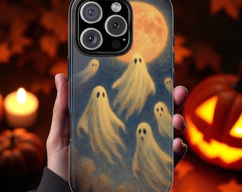 May include: A smartphone case featuring a Halloween-themed design. The case displays a full moon and several cartoon ghosts in a dark blue sky. The case is held in a hand, with a blurred background of pumpkins and candles.