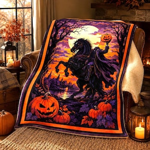 May include: A rectangular throw blanket featuring a headless horseman riding a black horse against a full moon and orange sunset. The scene includes carved jack-o'-lanterns, dark trees, and a distant castle silhouette, all framed by a bright orange border.