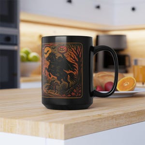 A striking mug featuring a haunting vintage-style illustration of the Headless Horseman riding beneath a full moon, pumpkin head glowing in eerie orange. The artwork captures twisted trees, bats, and gothic shadows in bold, fiery tones, wrapping around the mug for a dramatic Halloween aesthetic. Perfect for coffee, tea, or hot cider, this mug is both functional and a piece of gothic folklore art. Original design by The Haunted Hollow Co.™.