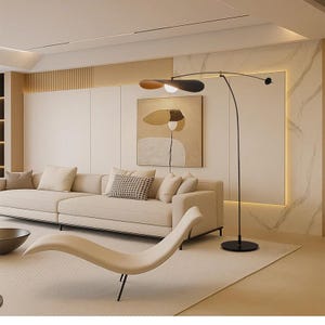 May include: Modern living room with a beige sofa, a chaise lounge, and a black floor lamp with a leaf-shaped shade. The room features a neutral color palette with a large abstract painting on the wall.