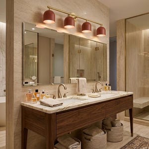 May include: A luxurious bathroom with a marble countertop vanity and a large mirror. The vanity has a dark wood finish and a double sink. Above the mirror is a light fixture with four red dome-shaped lights. A shower with glass doors is visible.
