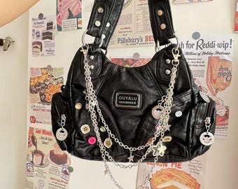 May include: Black faux leather shoulder bag with silver chain accents, buttons, and star charms. The bag features a top handle, multiple pockets, and the text "OUYALU XUXIANXILIE" on a small label. Decorative elements include buttons and charms.