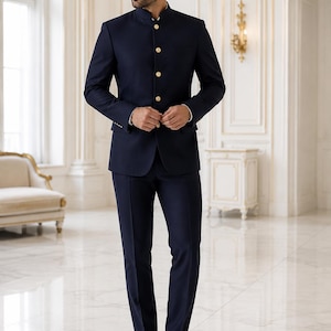 May include: A dark navy blue suit featuring a jacket with a mandarin collar and four gold-toned buttons down the front. The matching trousers are tailored with a straight-leg cut. The jacket includes long sleeves with small gold buttons at the cuffs.
