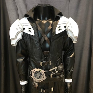 May include: Black leather cosplay costume with white shoulder armor and silver trim. The costume features a high collar, a belt with a circular buckle, and decorative accents. The costume is displayed on a black mannequin.
