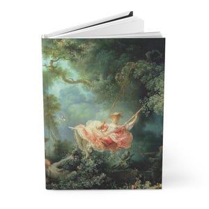 May include: Hardcover journal featuring a classic painting of a woman on a swing in a lush, green forest. The artwork showcases a woman in a pink dress, with a man in the background. The journal has a white interior and a black spine.
