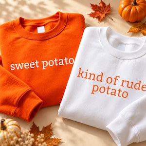 Puede incluir: Una sudadera naranja con el texto blanco sweet potato y una sudadera blanca con el texto naranja kind of rude potato. Ambas prendas cuentan con cuello redondo, mangas largas y puños acanalados, presentadas como un conjunto a juego.
