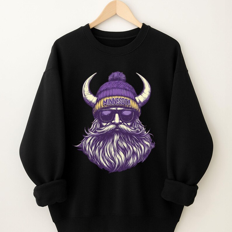 Pu&ograve; includere: Felpa nera con grafica di un vichingo con berretto viola, occhiali da sole e lunga barba viola. Sul berretto &egrave; stampata la scritta "Minnesota". Il vichingo ha grandi corna ricurve. La felpa &egrave; appesa a una gruccia di legno.