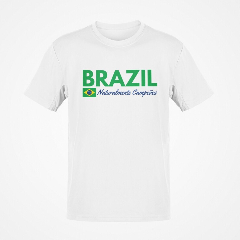 May include: White t-shirt with the word "BRAZIL" in green block letters. Below the word "BRAZIL" is the Brazilian flag and the words "Naturalmente Campe&otilde;es" in blue. The shirt is a crew neck style.
