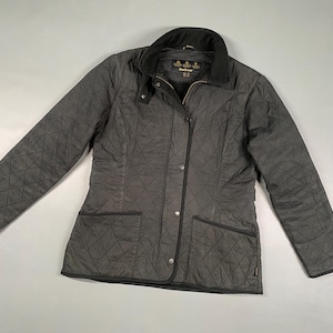 May include: A charcoal gray quilted jacket with a black corduroy collar, two front pockets, and a button-up closure. The jacket has a diamond pattern and a small logo on the front.