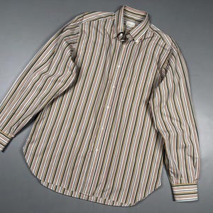May include: A long-sleeve button-down shirt featuring a vertical striped pattern in shades of brown, green, blue, and white. The shirt has a standard collar, a front button placket with white buttons, and buttoned cuffs on the long sleeves.