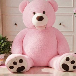 Peut inclure: Un grand ours en peluche rose avec un nez et des coussinets bruns. L'ours est assis, les jambes écartées, et sa langue est légèrement visible. C'est un jouet doux.