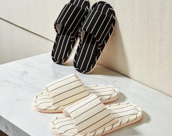 May include: Two pairs of striped slippers. One pair features black and white vertical stripes, while the other has cream and gray horizontal stripes. The slippers are made of soft fabric and have a comfortable design, perfect for indoor use.