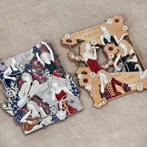 Peut inclure: Deux broches rectangulaires en émail métallique représentant plusieurs silhouettes d'une personne dans diverses tenues et poses. La broche de gauche présente des accents violets et argentés avec le texte Speak Now. Celle de droite a des motifs dorés et tournesols avec le texte Fearless.