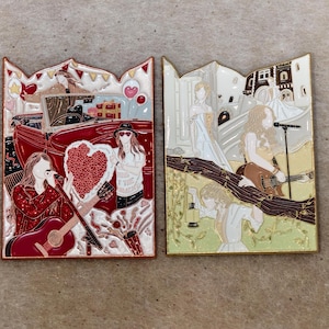 Op de afbeelding: Twee rechthoekige emaille pins met gedetailleerde illustraties. De linker pin toont een persoon die gitaar speelt, een rode cabriolet en een hartvorm. De rechter pin toont een persoon met een gitaar, een microfoon en een lantaarn.