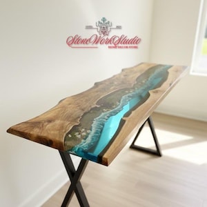May include: A wooden console table with a river-like design. The table features a live edge wooden top with a turquoise resin river. The base is made of black metal. The Stone Work Studio logo is visible.