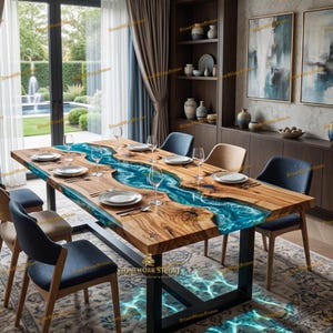 May include: A wooden dining table with a blue resin river design. The table is set with plates, silverware, and wine glasses. The table is supported by black metal legs. The room has a modern design with artwork and a view of a garden.