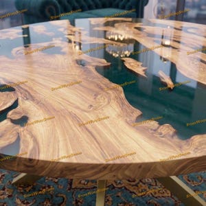 Pu&ograve; includere: Un tavolo rotondo in legno con un design a bordo vivo. Il tavolo presenta un fiume in resina epossidica verde scuro e gambe in metallo color oro. Il legno ha un motivo a venature naturali e il tavolo &egrave; posto su un tappeto fantasia.