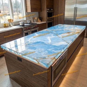 May include: A modern kitchen island with a striking blue and white countertop, resembling ocean waves. The island is made of dark wood and features a built-in microwave. The kitchen has wooden cabinets and stainless steel appliances.