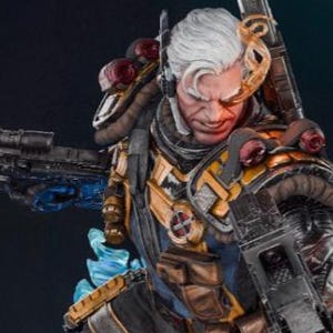 May include: A detailed statue of a character with white hair, wearing a tactical suit with gold and blue accents, and holding two large firearms. The figure is posed dynamically on a rocky base with blue energy effects.