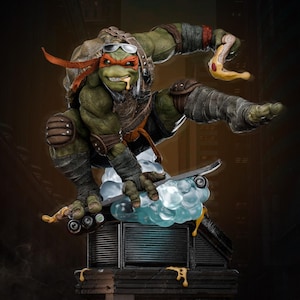 May include: A detailed statue of Michelangelo from Teenage Mutant Ninja Turtles, mid-air on a skateboard, holding a slice of pizza. The figure is green with an orange mask, brown armor, and sunglasses. The base is a cityscape.